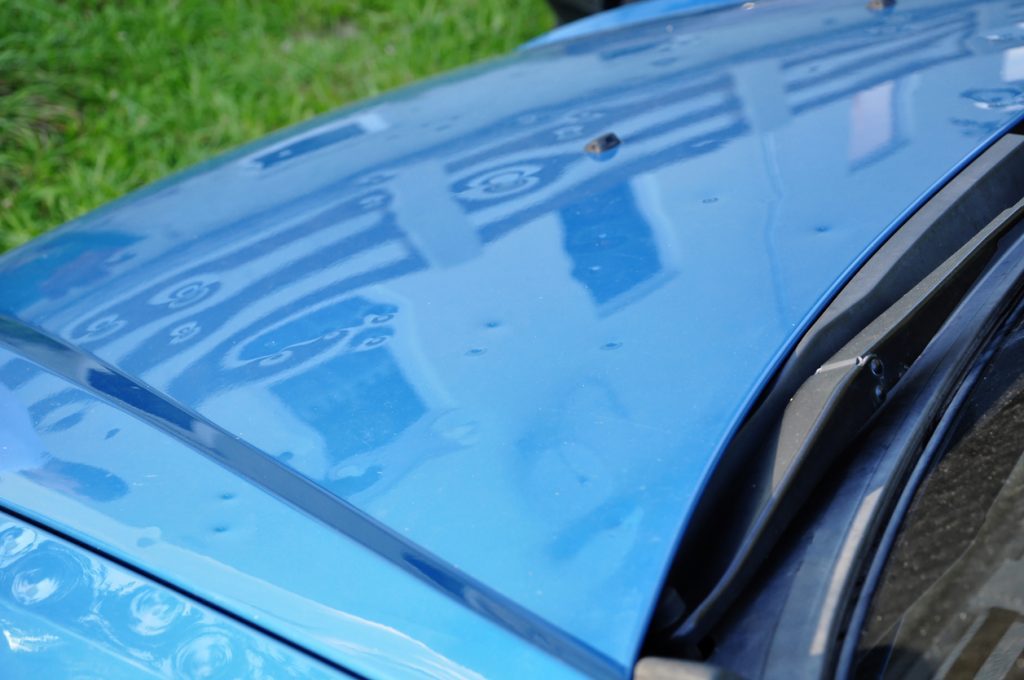 hail damage on the hood of a blue car