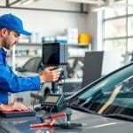 Technician calibrating auto glass in a modern repair shop, emphasizing quality service and certified expertise.