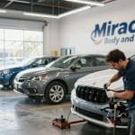 Technician working on vehicle repair in Miracle Body and Paint shop, with multiple cars in background, emphasizing auto body restoration and quality service in San Antonio.
