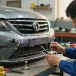 Auto body technician repairing a car bumper in a workshop, emphasizing professional service for bumper repair in San Antonio.