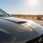 Car hood reflecting sunlight, emphasizing paint protection and vehicle maintenance in hot Texas climate.