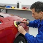 Auto body technician polishing a red car, demonstrating high-quality scratch repair techniques relevant to Miracle Body and Paint's collision repair services in San Antonio.